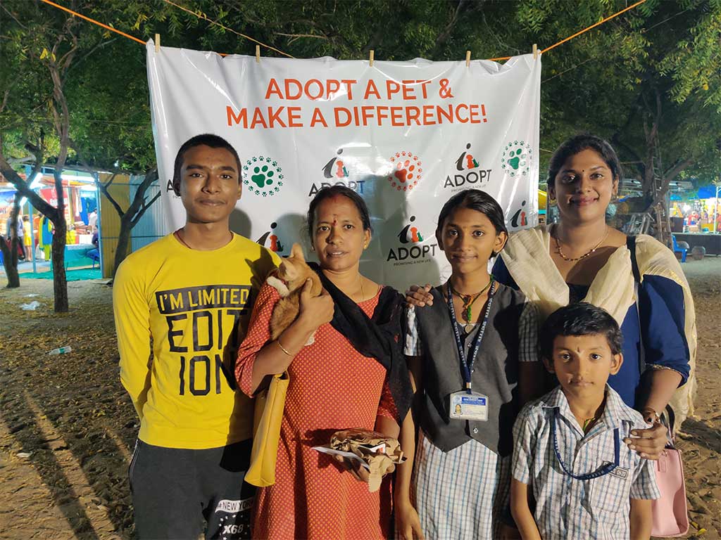 A family with their adopted pet and iAdopt volunteers at an adoption drive